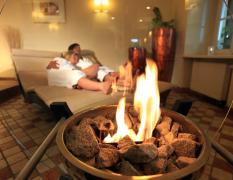 Zwei Gäste kuscheln im Ruheraum mit offenem Kamin im Romantik Hotel Im Weissen Rössl